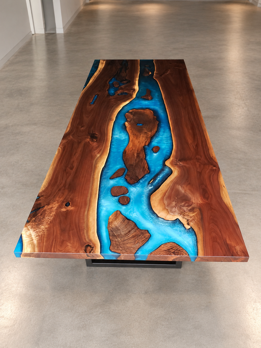 Custom black walnut dining table with a bright blue resin river and black metal base in a clean showroom.