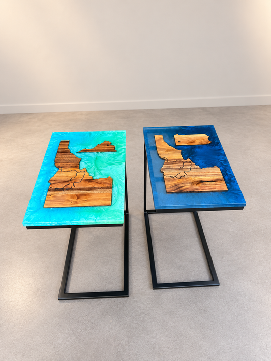 Pair of custom state-map wood and blue resin C-tables in a clean, neutral showroom.