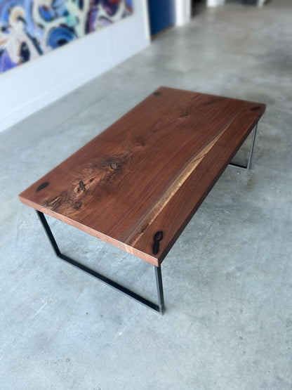 Handcrafted walnut coffee table with natural grain and black metal base in the WoodLab workshop