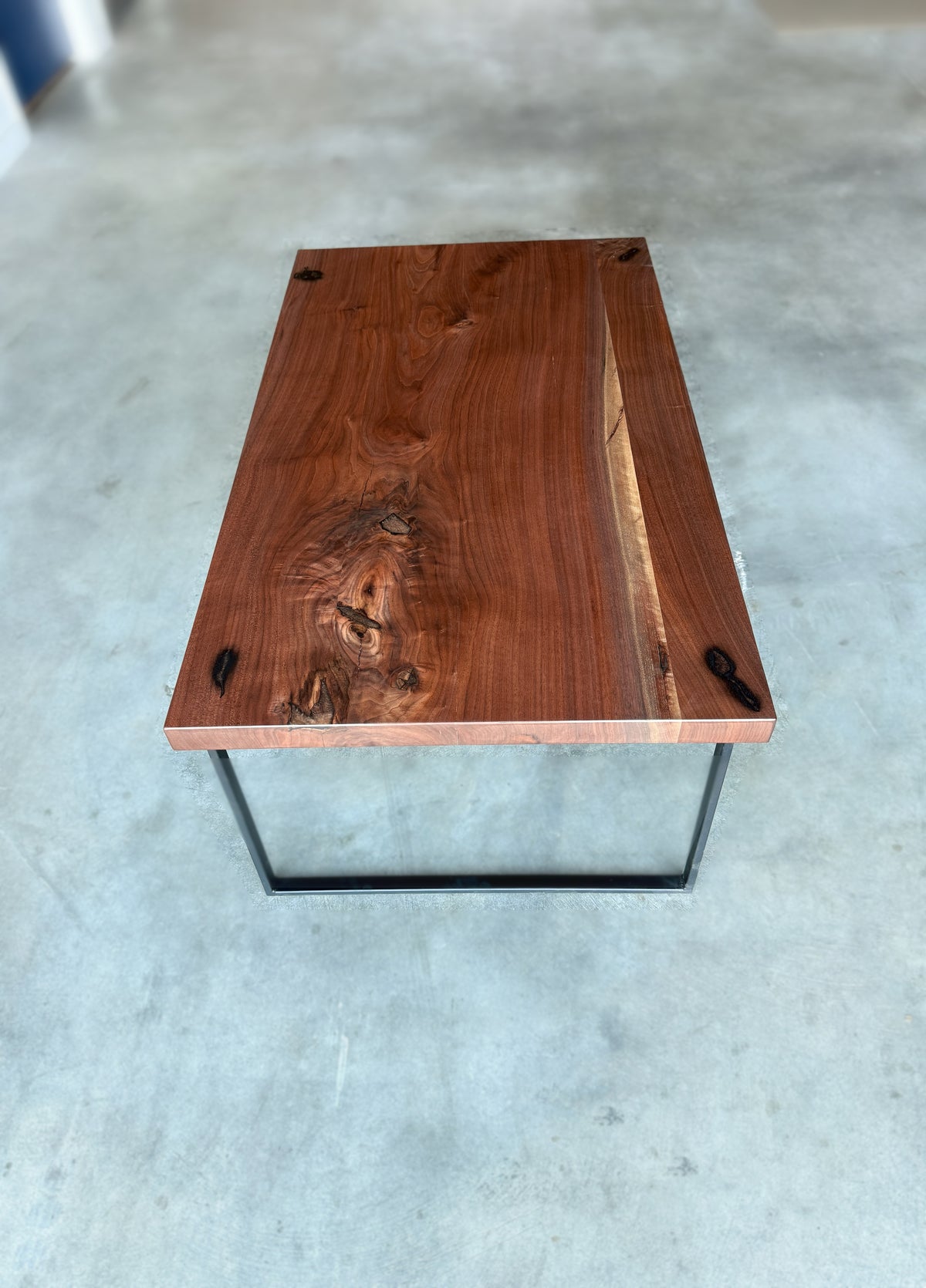 Top view of walnut coffee table showing natural grain, knots, and black metal base